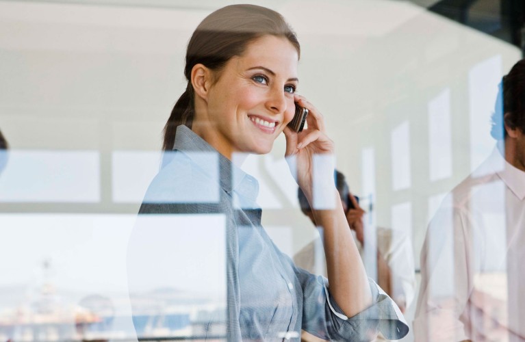 Blick durch eine Fensterscheibe auf eine telefonierende Businessdame.